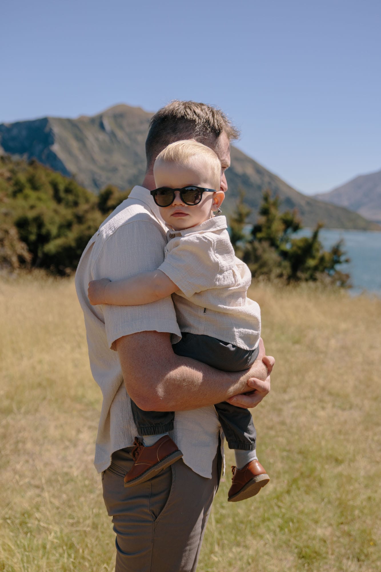 A child in sunglasses on their father’s shoulders