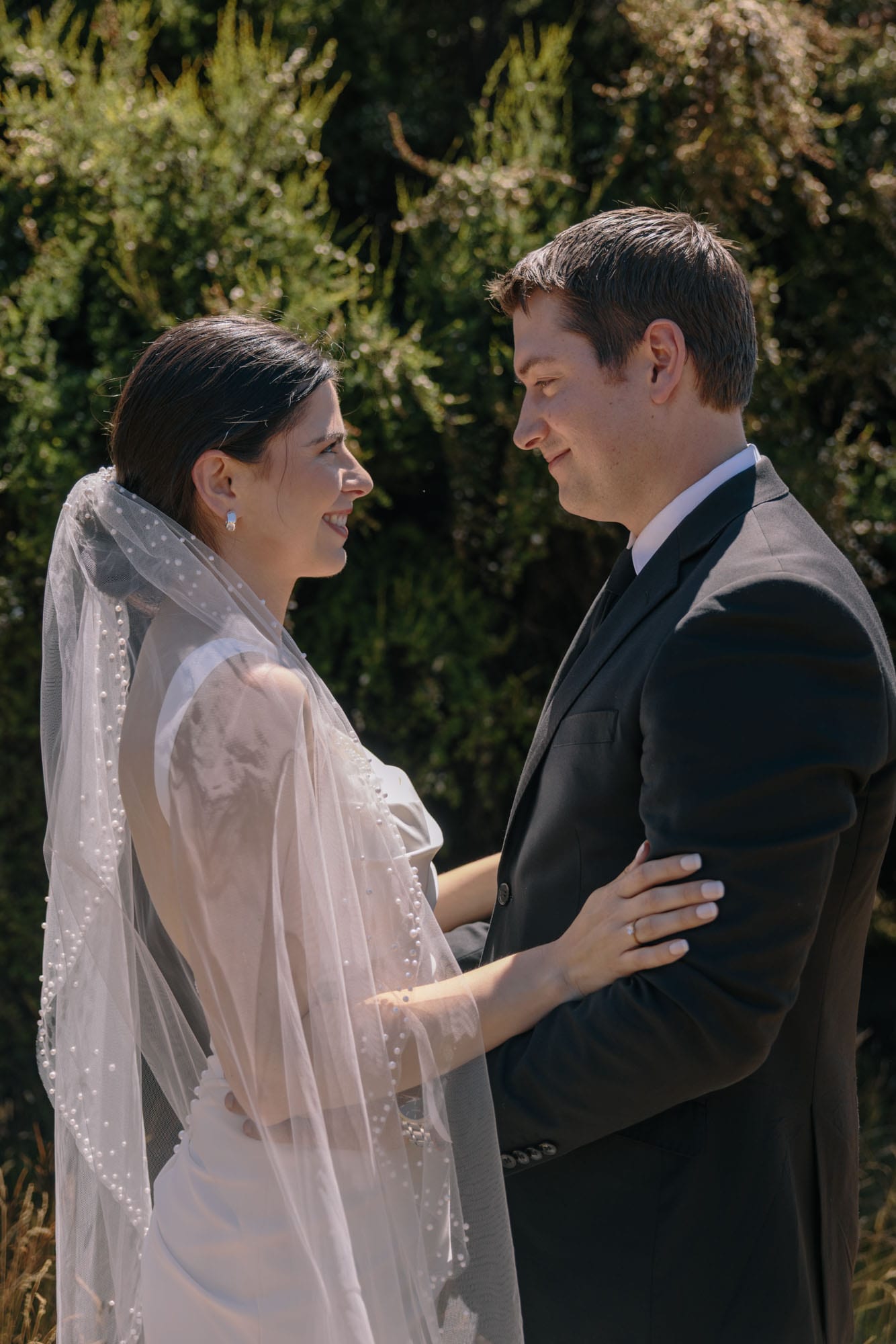 A couple in veil and black suit standing close together